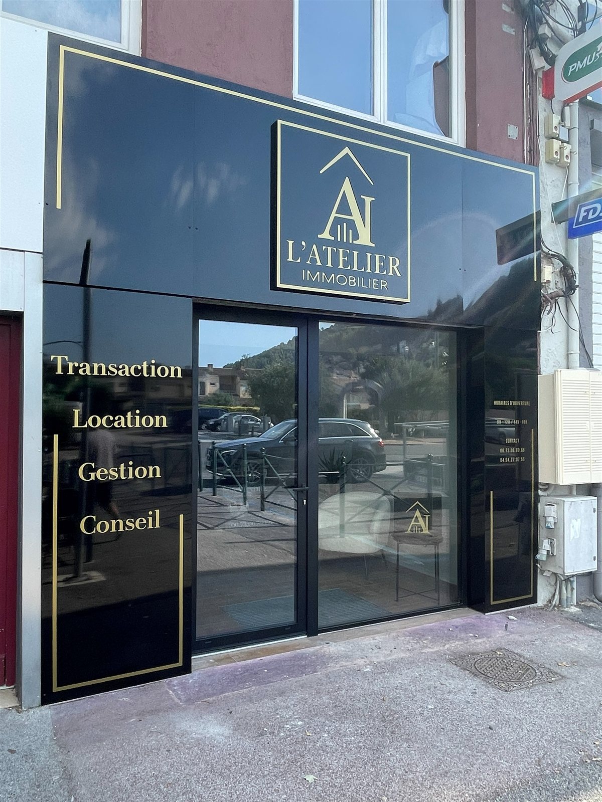 L'Atelier Immobilier à Solliès-Toucas : Habillage de façade noir et or, caisson logo en relief