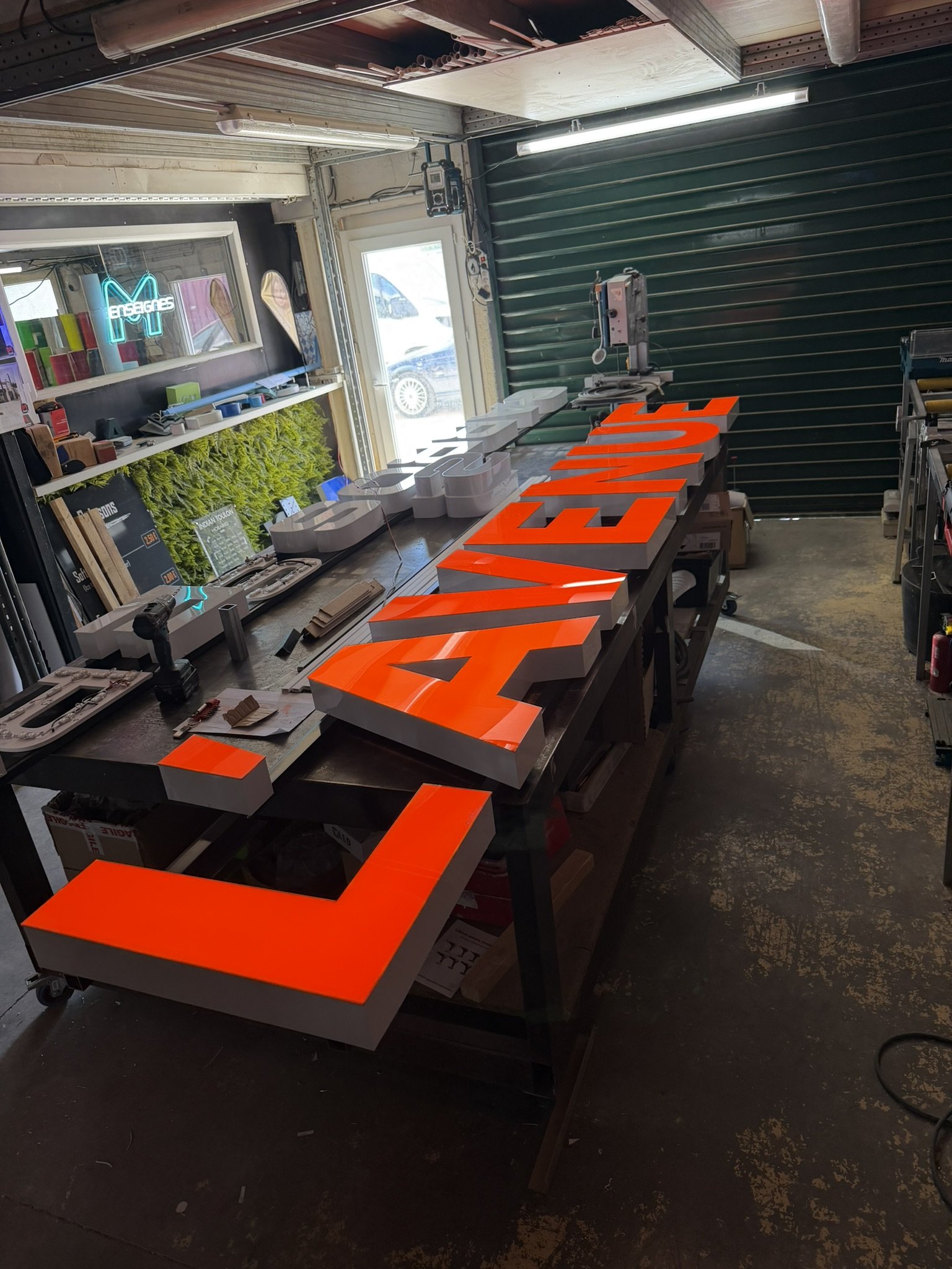Lettres boîtier orange de L'Avenue Carrosserie sur l'établi de l'atelier de Cuers