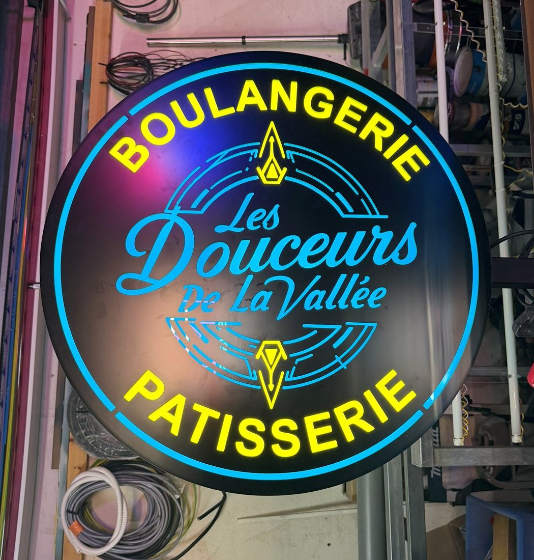 Enseigne drapeau ronde Les Douceurs de la Vallée de Solliès-Toucas allumée à l'atelier avant la pose