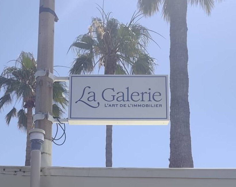 La Galerie à Hyères : Enseigne drapeau sur poteau entre les palmiers