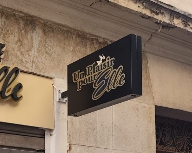 Enseigne drapeau noir et or Un Plaisir pour Elle dans le centre ancien de Toulon