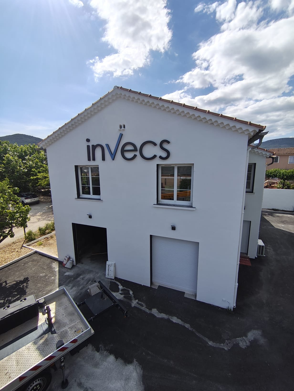 Bâtiment Invecs à Cuers vu de biais, lettres noires en plexiglas jour et nuit en haut du pignon blanc