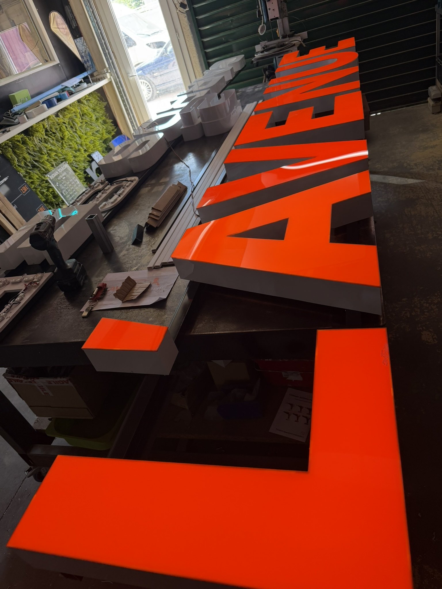 Grandes lettres boîtier L'AVENUE à face en plexiglas orange, en fabrication sur l'établi de l'atelier de Cuers