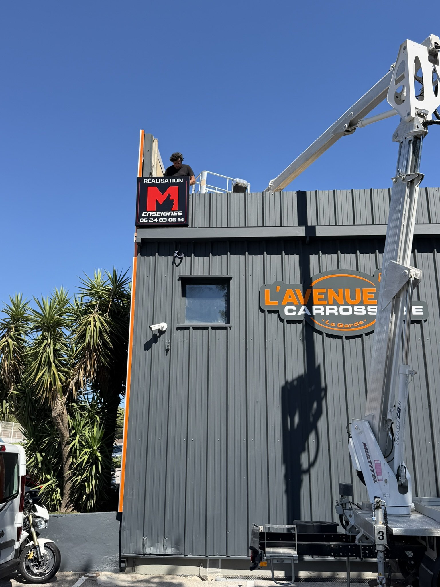 Panneau dibond découpé à la forme du logo L'Avenue Carrosserie sur le bardage latéral, à La Garde