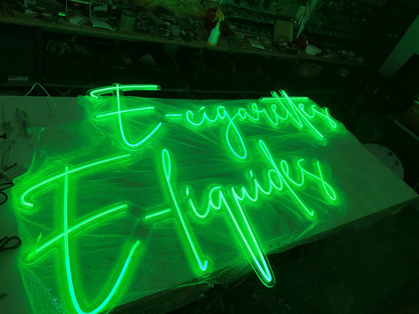 Néons LED E-cigarettes et E-liquides allumés en vert sur l'établi pendant la fabrication