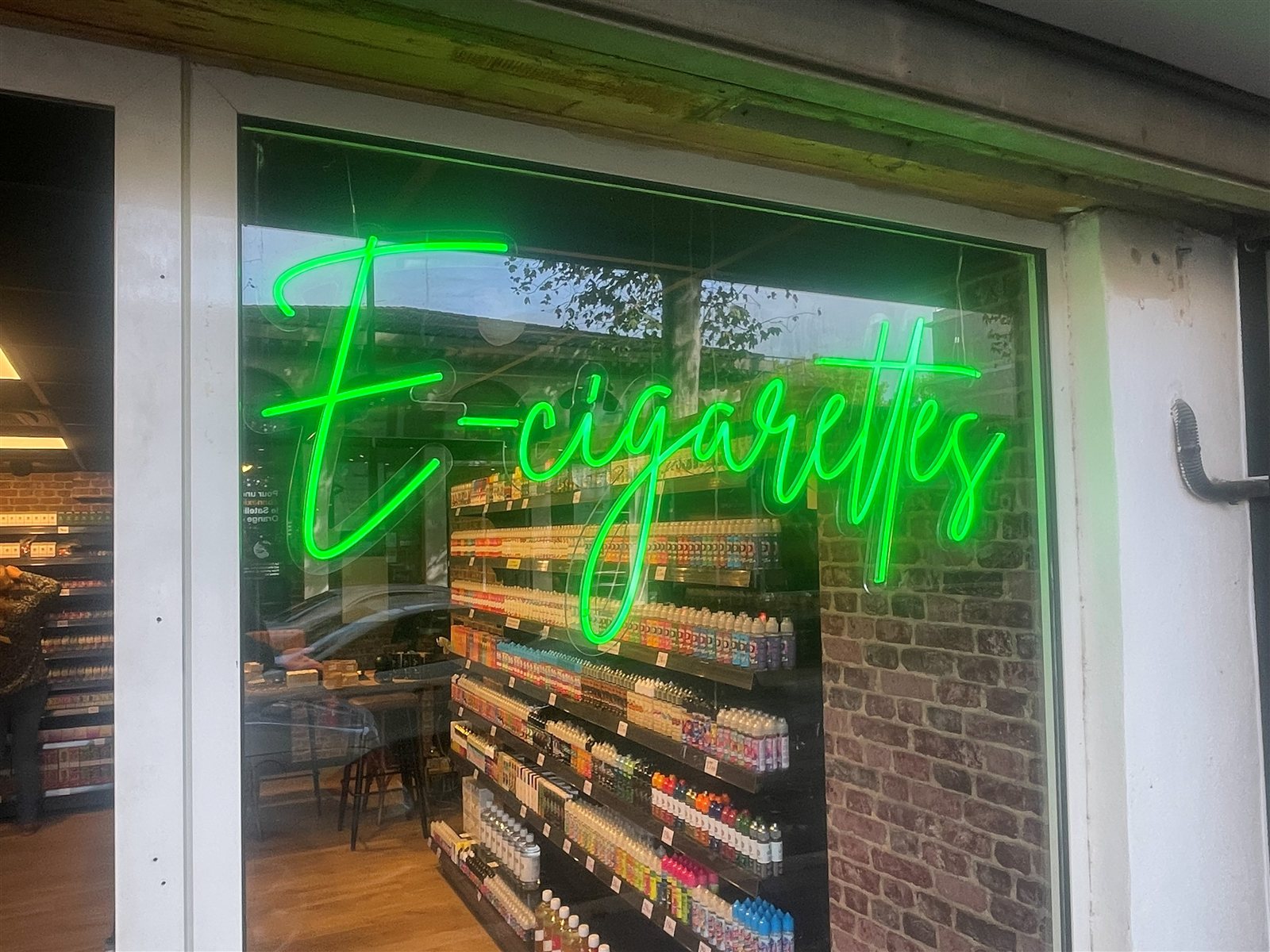 Néon LED E-cigarettes vert suspendu derrière la vitrine d'une boutique