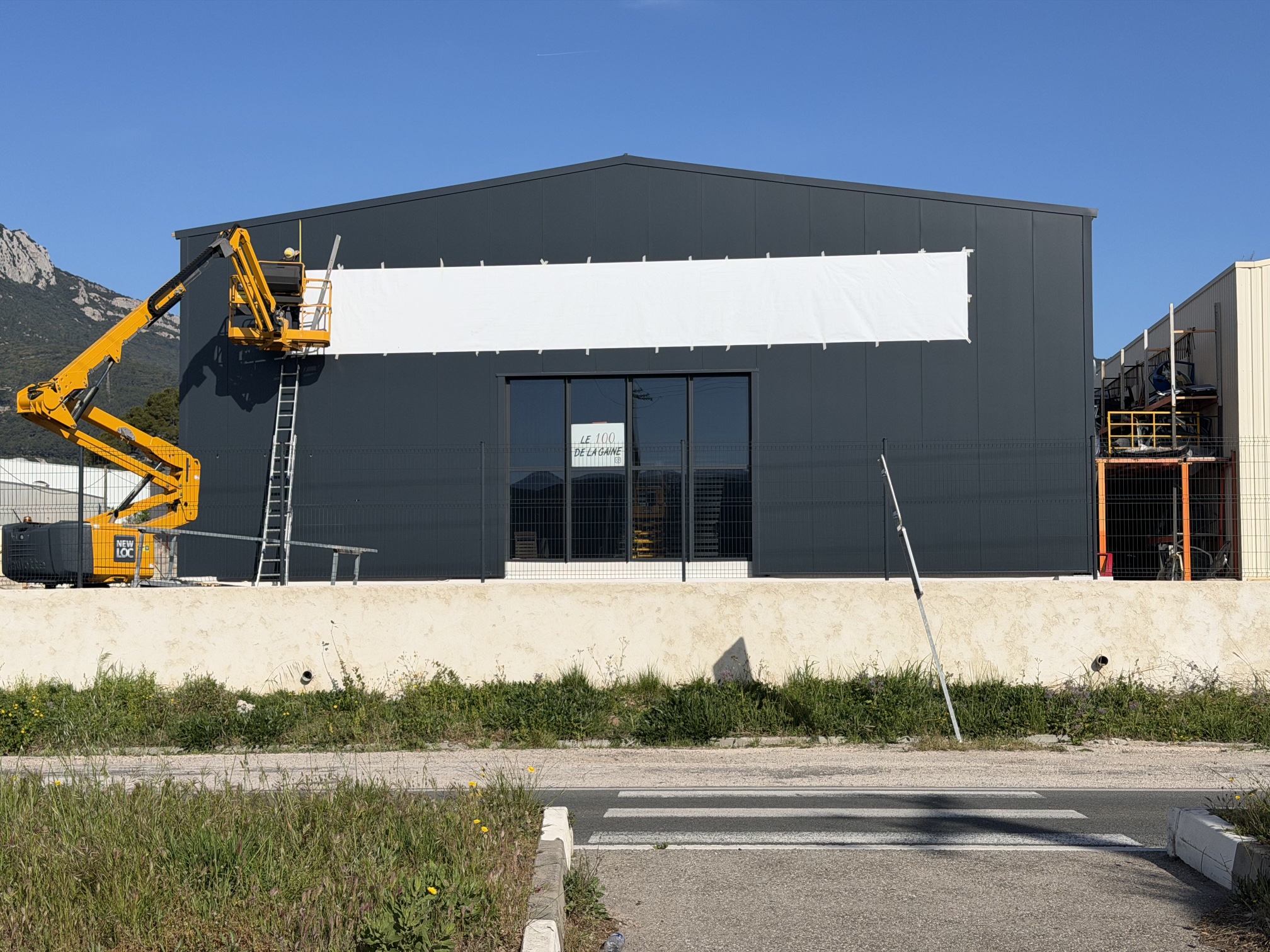 Pose à la nacelle sur le pignon du Showroom Carrelage à La Farlède, gabarit en place sur le bardage