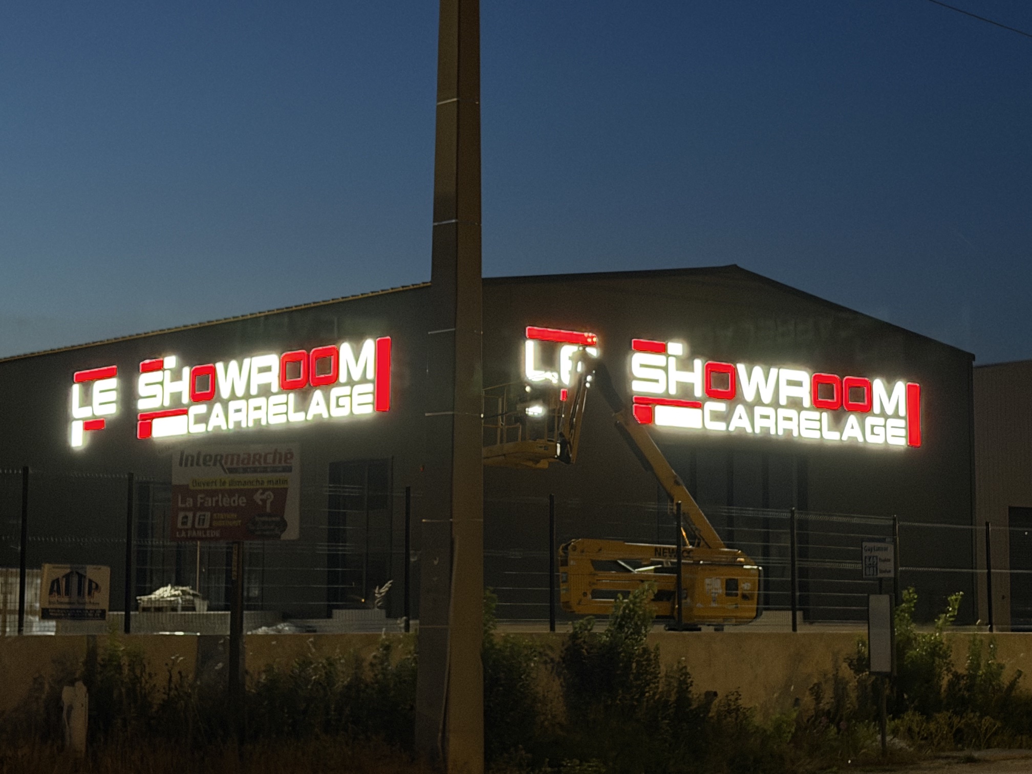 Le Showroom Carrelage allumé vu depuis l'avenue de la zone d'activités de La Farlède