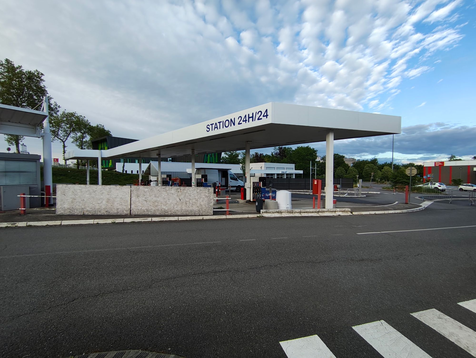 Auvent blanc de la station-service d'Aurillac avec le lettrage bleu Station 24h/24